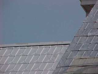 Old roof being primed next to new shingle addition